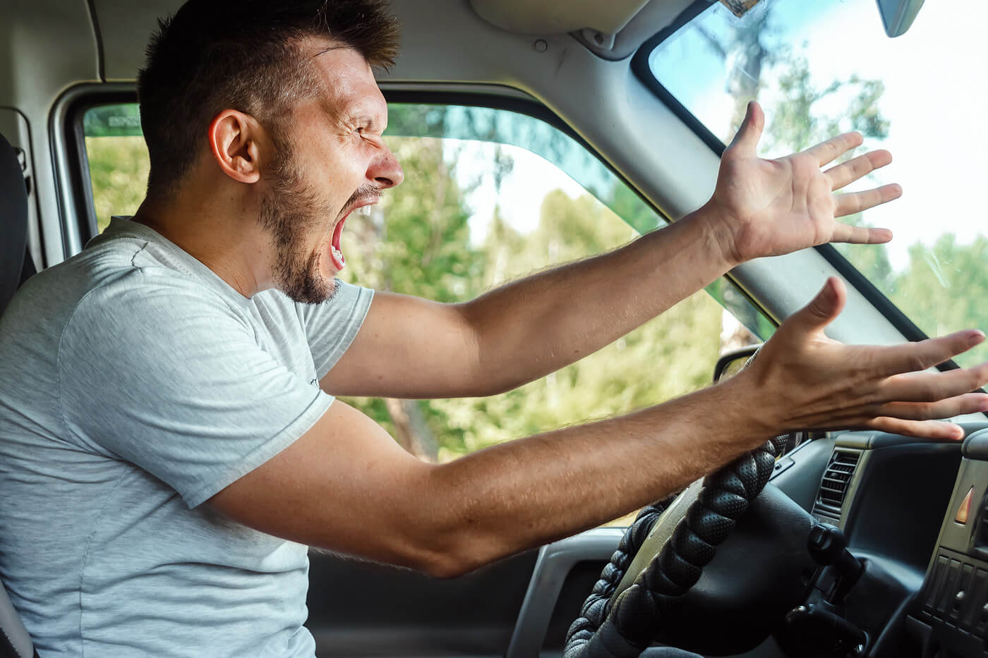 Man screaming and aggressively gesturing behind the wheel, showing extreme road rage behavior. Anger Management 818.