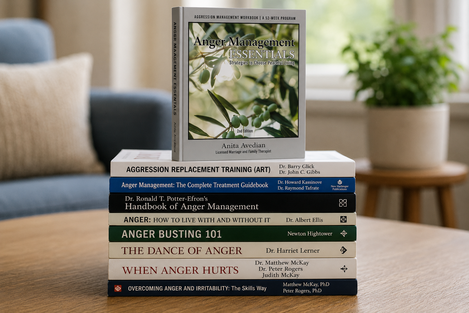 A stack of eight books on anger management is placed on a table, with the top book titled "Anger Management Essentials" standing upright. A plant is visible in the background.