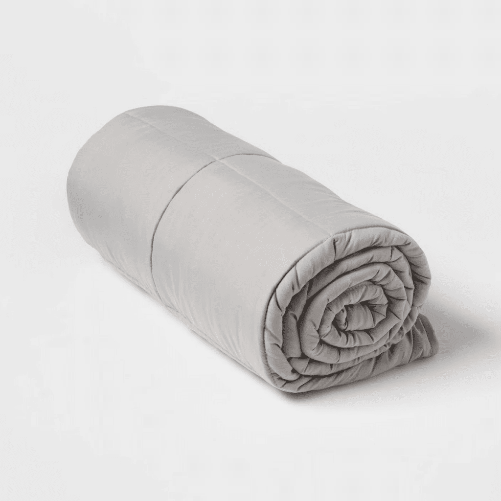 A neatly rolled, light gray comforter on a plain white background.