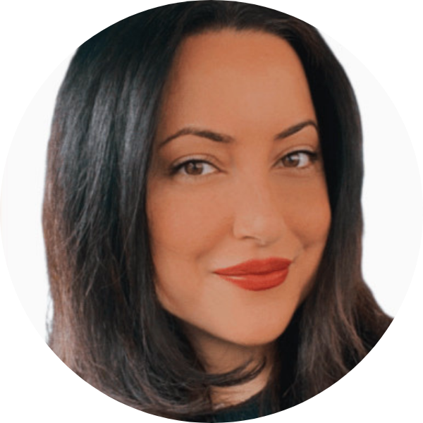 Portrait of a woman with long dark hair, light skin, brown eyes, and red lipstick, facing the camera and smiling slightly. White background.